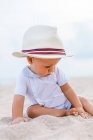 Vista frontal de um bebê na praia com um chapéu — Fotografia de Stock