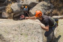 Aventureiros escalando montanha, vestindo arnês de segurança contra a paisagem pitoresca — Fotografia de Stock