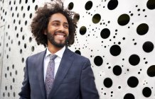 Cheerful african american entrepreneur standing next to holey wall — Stock Photo