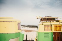 Барвистий мікроавтобус з трейлером, припаркований на піщаному березі в сонячний день — стокове фото
