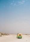 Minibús colorido con remolque estacionado en la orilla de arena en el día soleado - foto de stock