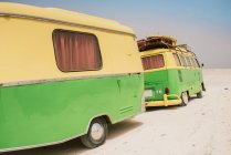 Minibús colorido con remolque estacionado en la orilla de arena en el día soleado - foto de stock