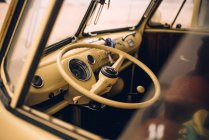 Driving wheel of retro yellow car in empty cabin through window glass — Stock Photo