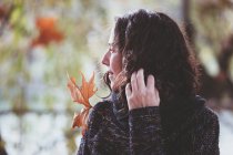 Frau mit lockigem Haar schaut weg auf verschwommenem Hintergrund des friedlichen Herbstparks — Stockfoto