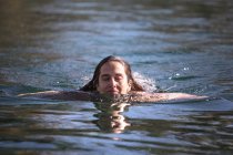 Mulher adulta com olhos fechados nadando em água morna limpa da lagoa no spa e desfrutando de sol durante o dia — Fotografia de Stock