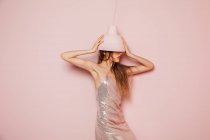Vista frontal de uma jovem posando sob uma lâmpada no fundo rosa — Fotografia de Stock