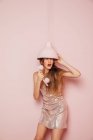 Vista frontale di una ragazza di moda con un telefono in mano su una parete rosa — Foto stock