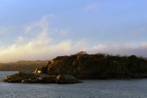Tranquilo litoral com rochas rocha no lago em raios solares — Fotografia de Stock