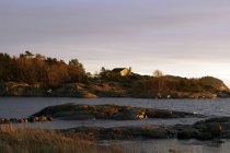 Pedras cinzentas e casa à beira-mar tranquila no dia frio com céu colorido claro — Fotografia de Stock