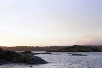Серые камни на мирном берегу в холодный туманный день с легким и ясным небом — стоковое фото