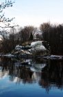 Flussseite mit Schnee bedeckt und blattlose Bäume, die sich im stillen Wasser spiegeln — Stockfoto