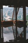 Barcos de madeira amarrados no cais perto de escadas no lago com água cristalina tranquila no belo fundo da montanha nebulosa e floresta densa verde em Dolomitas — Fotografia de Stock