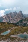 Two lakes with pure blue water on green rocky hills on background of gray mountains in Dolomites during clear weather — Stock Photo
