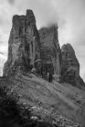Schwarz-weißer Blick von den Ausläufern mit grünem Gras und kleinen Felsen nebliger Berggipfel Drei Zinnen in den Dolomiten bei bewölktem Wetter — Stockfoto