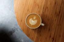 De cima xícara de cappuccino fresco com forma de coração na espuma servida na mesa de madeira no café — Fotografia de Stock