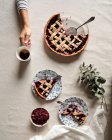 Сверху кукурузник сидит за крытым столом с подаваемым кофе и вкусным пирогом из ягод на белом фоне — стоковое фото