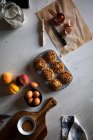 Зверху склад смачних кексів з волоськими горіхами у випічці страви яйця персики борошно та пергаментний папір, розташовані на білій поверхні — стокове фото