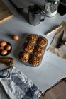 Von oben Zusammensetzung von leckeren Cupcakes mit Walnüssen in Backform Eier Pfirsichmehl und Pergamentpapier auf weißer Oberfläche angeordnet — Stockfoto