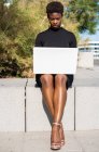 Concentrated African American woman in elegant black dress using laptop on pavement — Stock Photo