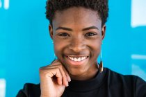 Portrait of African American smart woman looking in camera standing near blue background — Stock Photo
