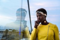 Side view of serene African American woman chilling on glass balcony and looking away — Stock Photo