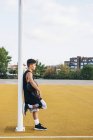 Young man leaning on post on basketball court outdoors. — Stock Photo