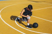Junger Mann und Ball dehnen sich auf Basketballfeld im Freien. — Stockfoto