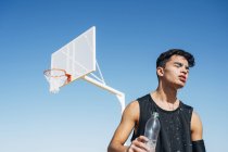 Молодой человек на баскетбольной площадке льет воду из бутылки на лицо . — стоковое фото