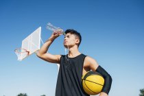 Jeune homme sur le terrain de basket versant de l'eau de bouteille sur le visage
. — Photo de stock