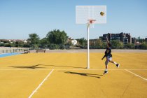 Молодой человек играет на баскетбольной площадке на открытом воздухе . — стоковое фото