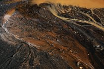 From above abstract dark ground with dirty puddle and dripping rusty water flows — Stock Photo