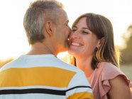 Adult man hugging woman and kissing while standing on beach — Stock Photo