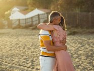 Взрослые мужчины и женщины смеются и обнимаются, веселясь на песчаном берегу курорта — стоковое фото