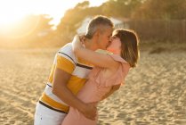 Homme et femme adultes excités s'embrassant et s'embrassant sur la rive sablonneuse de la station balnéaire — Photo de stock
