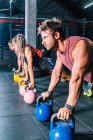 Vue latérale des sportifs forts faisant de l'entraînement avec du poids dans la salle de gym — Photo de stock