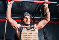 Homem forte fazendo exercício pull-up com peso na barra horizontal — Fotografia de Stock