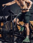 Сильные мужчины тренируются на современном велотренажере в спортклубе — стоковое фото