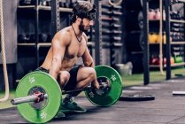 Homme fort et athlétique faisant l'entraînement d'haltère dans la salle de gym moderne — Photo de stock