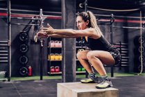 Mulher atlética pulando na caixa para melhorar a resistência no ginásio — Fotografia de Stock