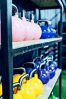 Set of colorful kettlebells on shelves in modern health club - foto de stock