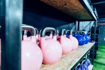 Set of colorful kettlebells on shelves in modern health club — Stock Photo