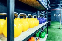 Set of colorful kettlebells on shelves in modern health club — Stock Photo