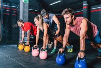 Athletic strong fellows doing workout with weight in gym — Stock Photo