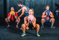 Athletic strong fellows doing workout with weight in gym - foto de stock