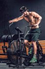 Сильний чоловік тренується на сучасному тренувальному велосипеді в спортивному клубі — стокове фото