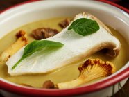 Крупним планом смачний грибний крем-суп з прованськими травами, прикрашеними листям свіжого базиліка — стокове фото