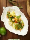 Top view of artisan ravioli pasta served with herbal sauce and nuts on leaf-shaped plate on timber table — Stock Photo