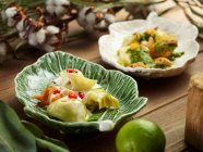 Керамические листообразные тарелки с вкусными равиоли, подаваемые с соусом песто — стоковое фото
