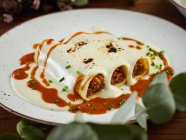 Close-up of hake and txangurro cannelloni with oxtail served with bechamel sauce on ceramic plate — Stock Photo
