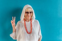 Portrait of beautiful stylish white-haired senior woman with sunglasses in white shirt with hood on head and coral beads — Stock Photo
